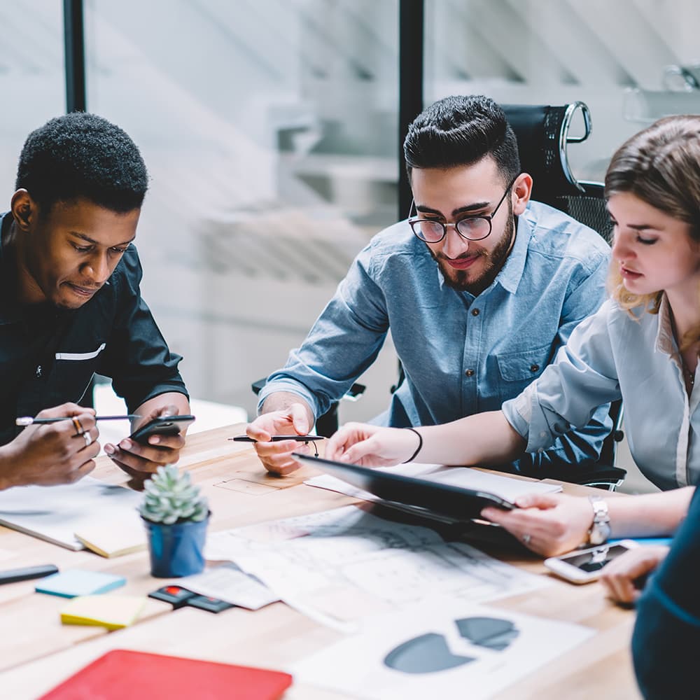 A group of men and women sit around a conference table full of papers