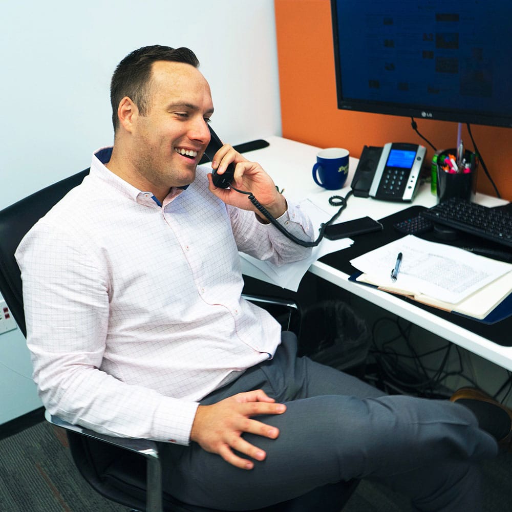 A businessman sits at his desk talking on the phone
