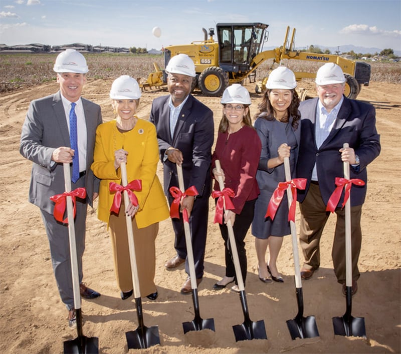 A group of people poses in business clothes pose with ribboned shovels